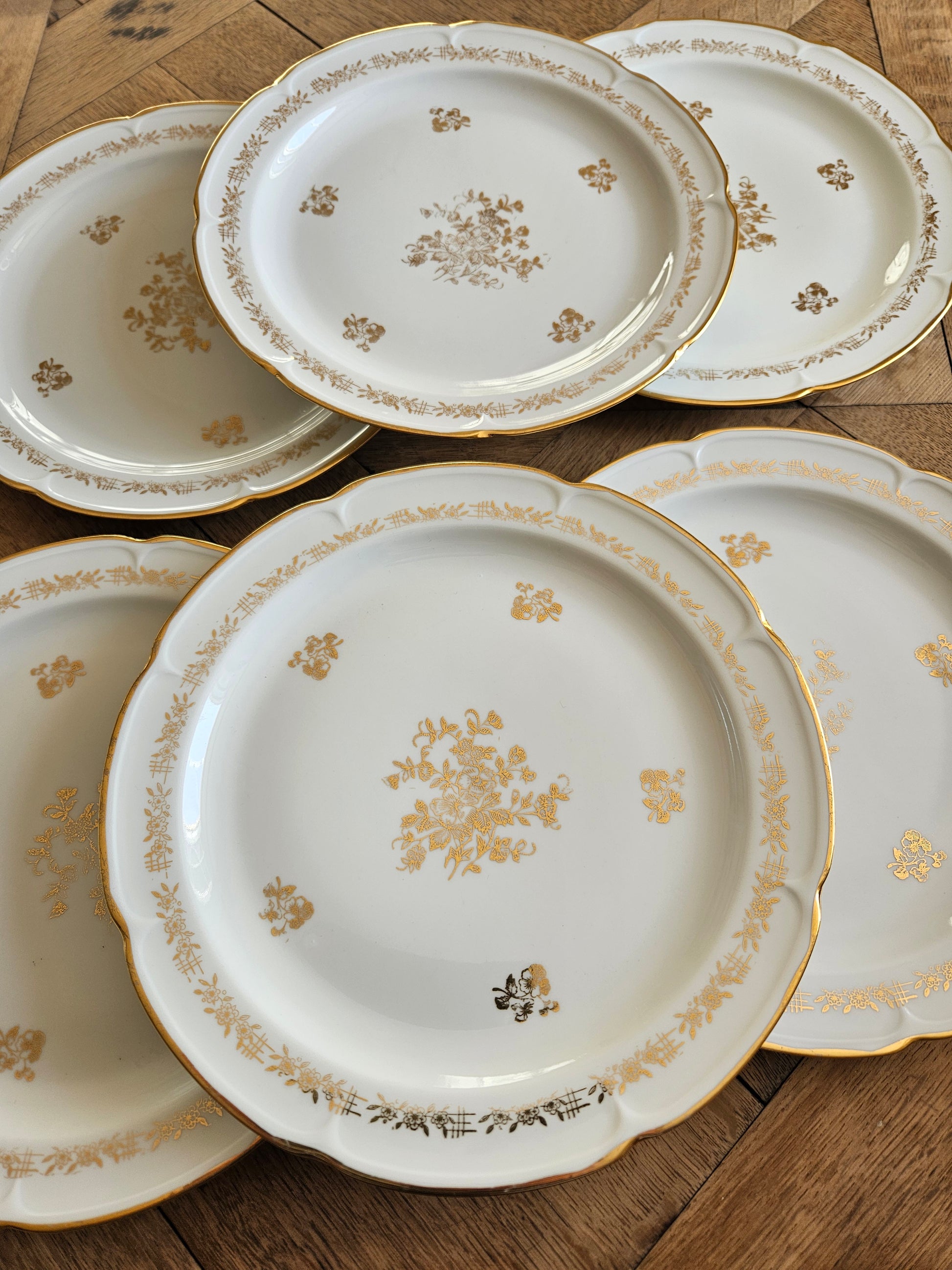 Lot de 6 assiettes plates anciennes en porcelaine de Vierzon. Décor floral blanc et doré. Idéales pour une élégante table de fête. 