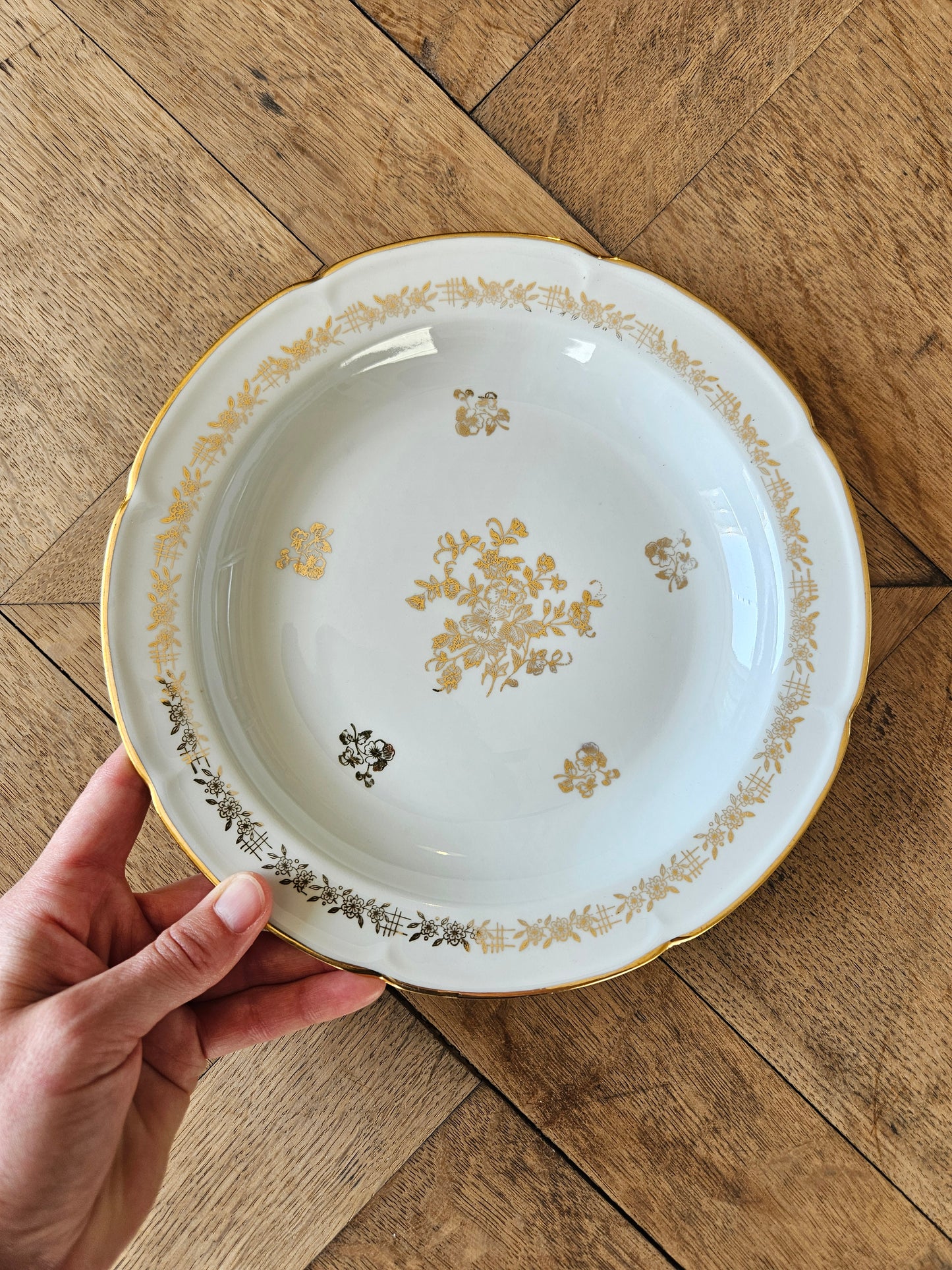 Assiette creuse ancienne en porcelaine de Vierzon. Décor floral blanc et doré idéal pour une table de fête élégante et raffinée. 