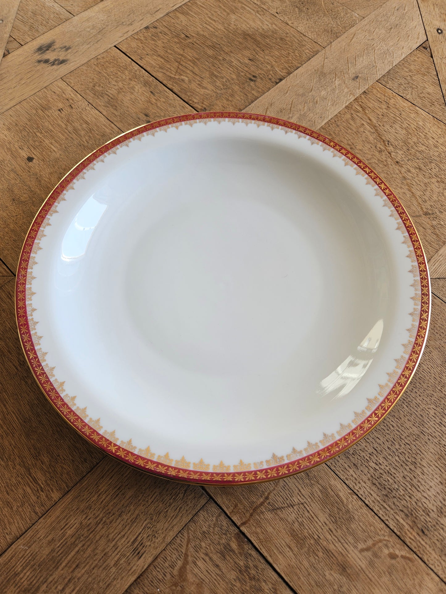 Plat creux vintage en porcelaine, décor rouge et or. Élégance et raffinement.